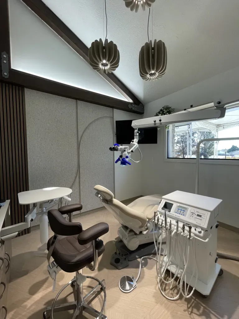 Modern endodontic operatory with dental chair, microscope, and pendant lighting